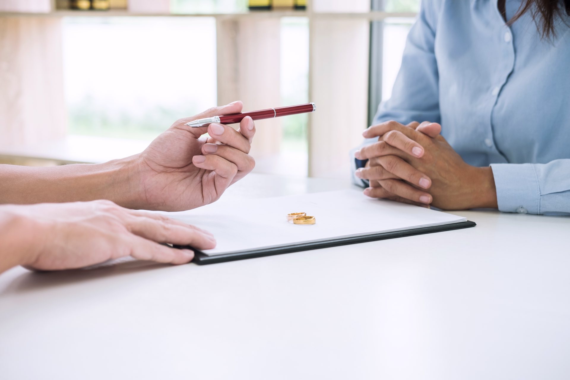 Zoomed in on two people filing out paperwork with rings on top of the paperwork