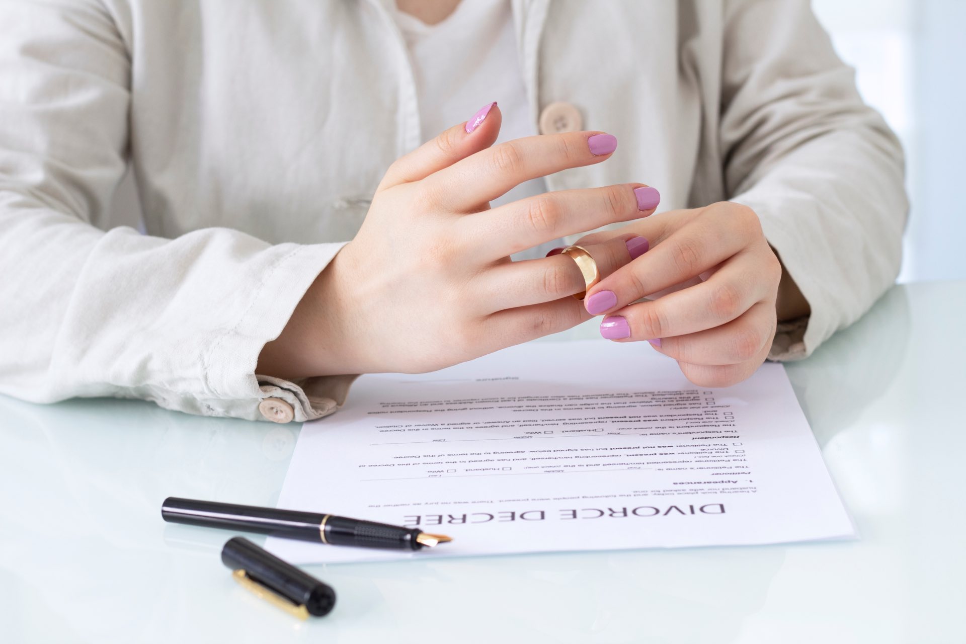 Divorce decree paperwork with a pen and a zoomed in picture of hands and a wedding ring