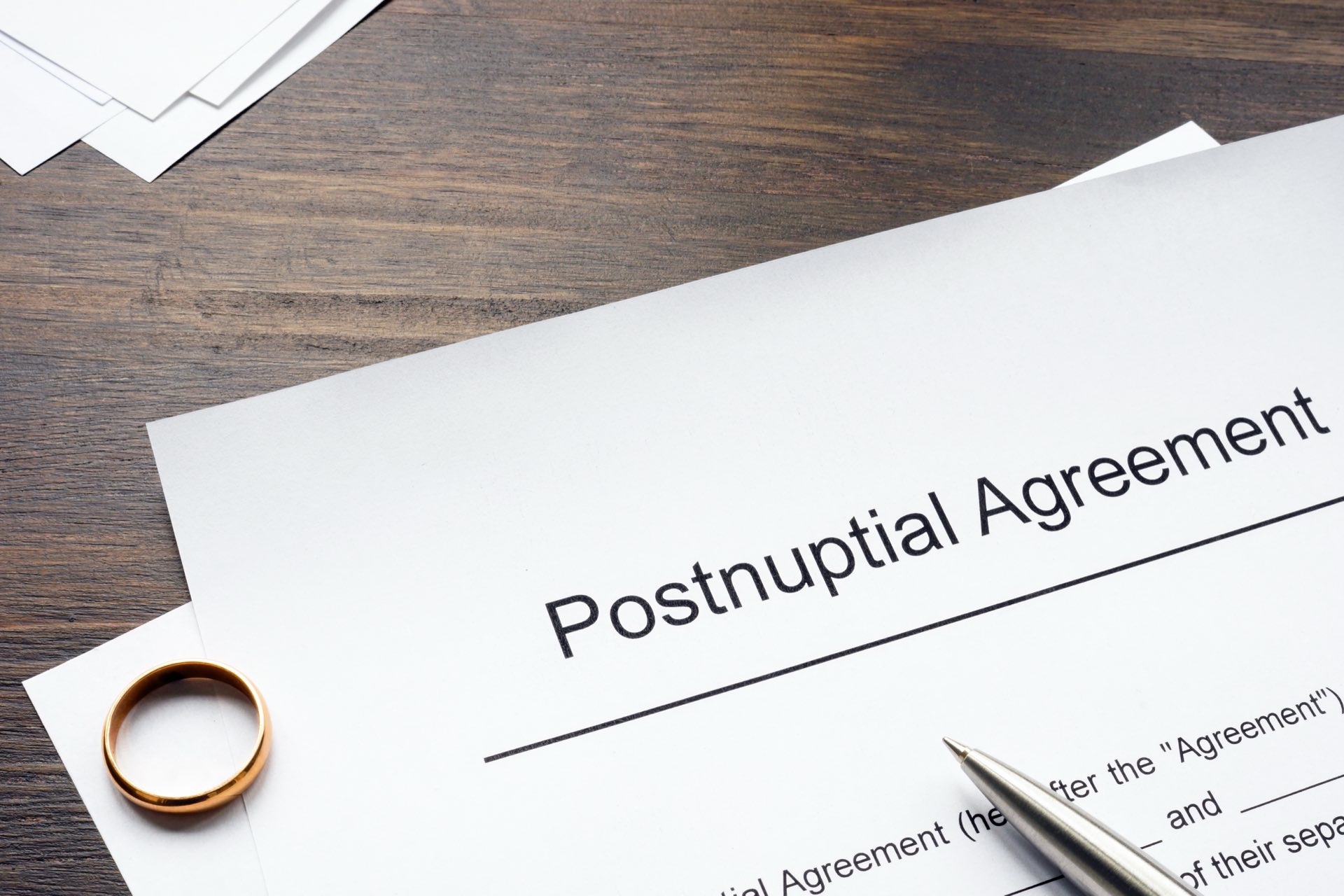 Paperwork that says Postnuptial Agreement with a wedding ring on it