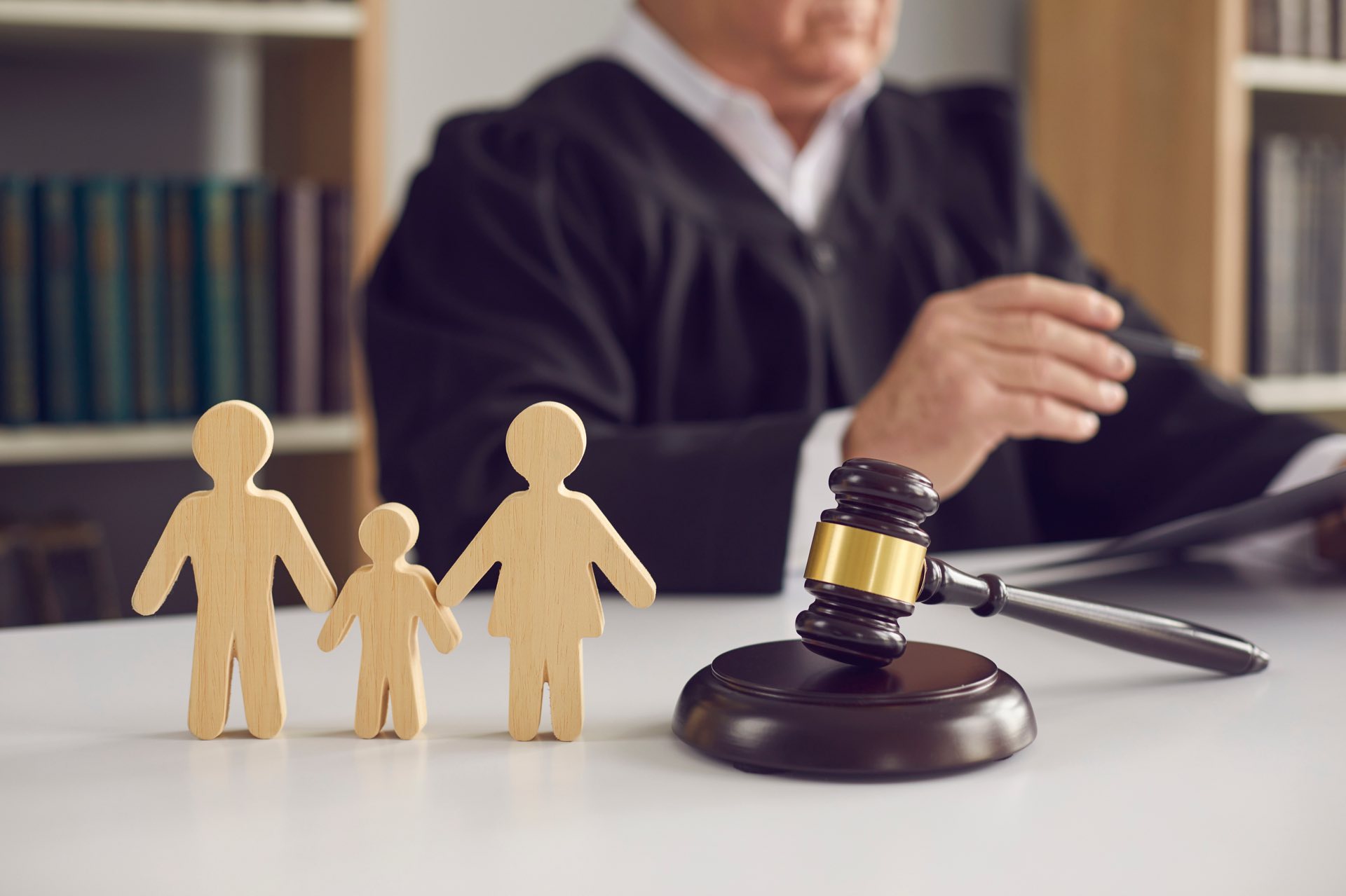 Gavel and small wooden family with a judge in the background