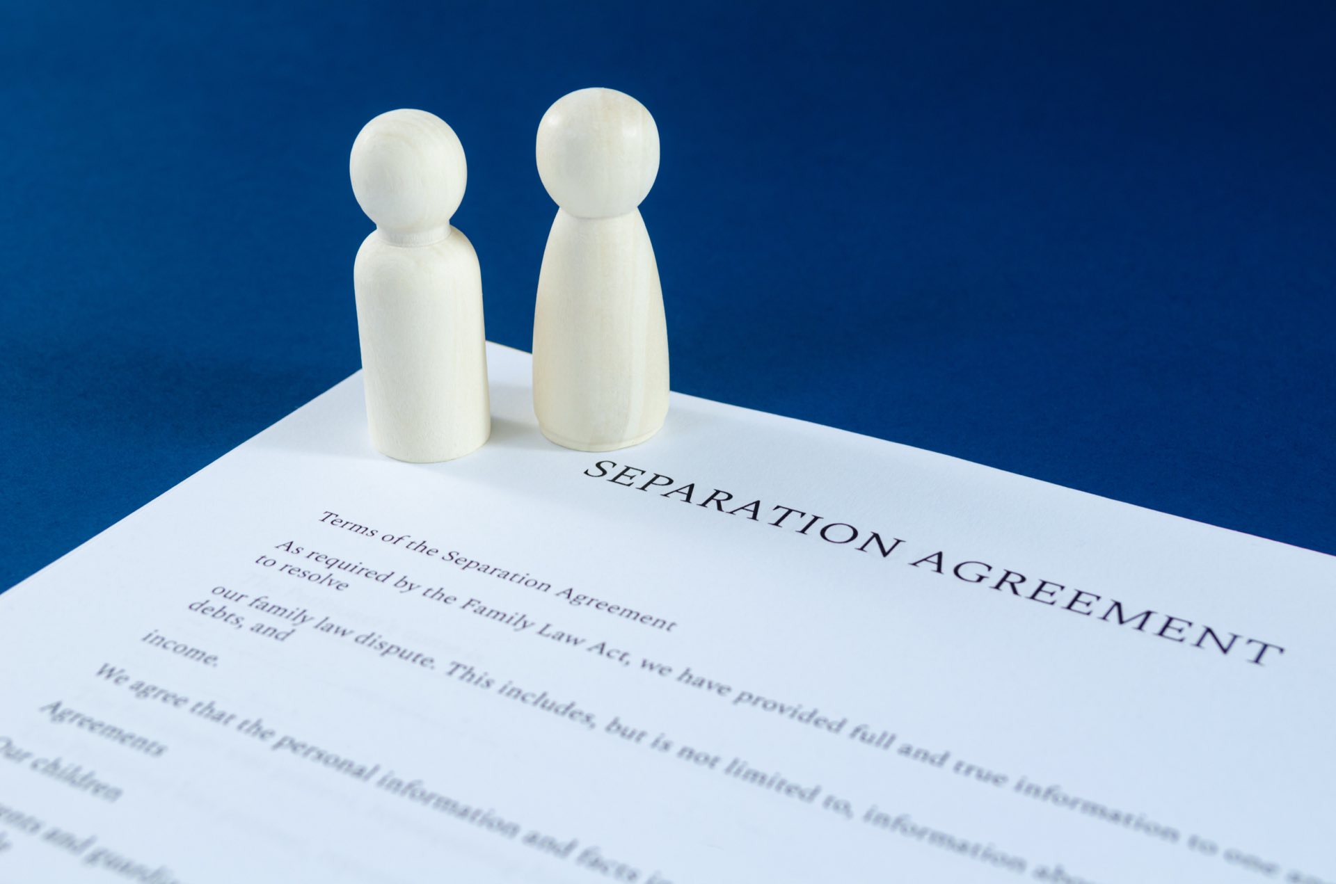 Male and female wooden figures on top of a separation agreement
