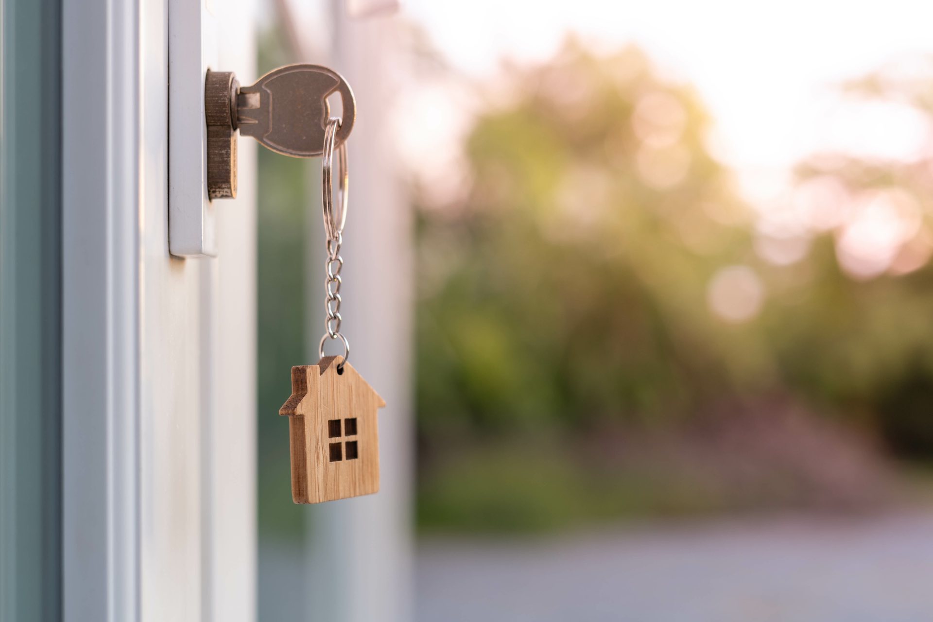 A house key with a wooden house as the keychain inside a keyhole
