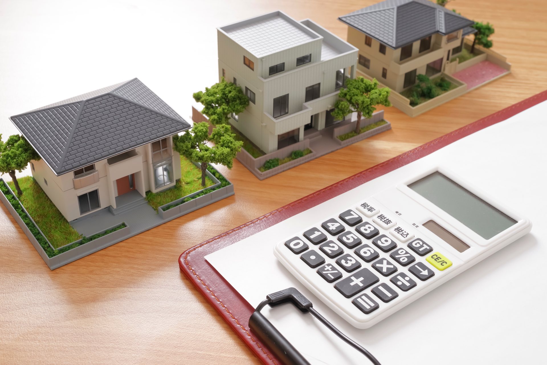 Small wooden house next to a clipboard and calculator